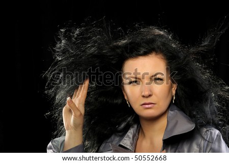 Model with beautiful long hair in motion created by wind. Blsck background