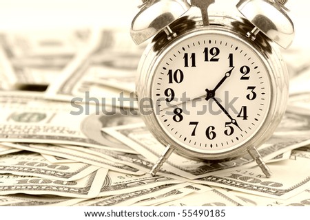 Time - money. Business concept. Analog hours on a heap of paper dollars. Old tone