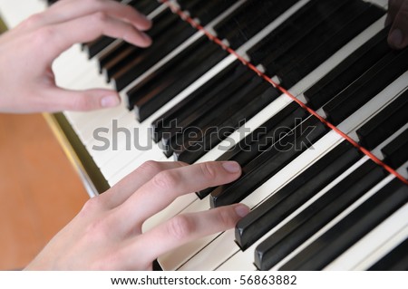 Hands above keys of the piano. A photo close up.