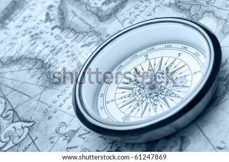 Old compass on ancient map. Blue toned image