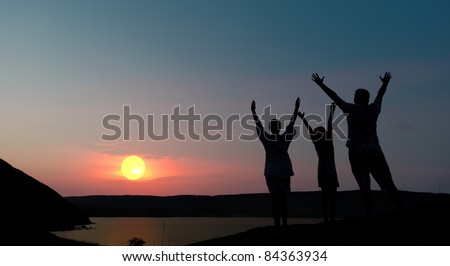 The family from three persons welcomes the sunset sun.