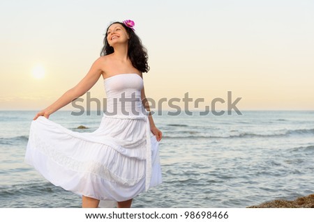 The woman in a white sundress on seacoast. Sunset illumination