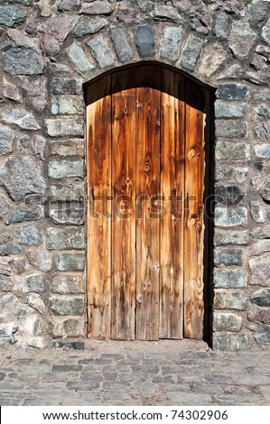 old wood door in a stone wall of an ancient building of an abandoned mountain village