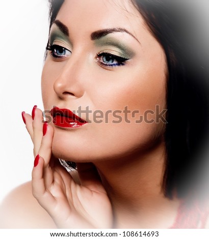 portrait of a beautiful brunette girl with healthy beautiful hair and  glossy face, whith a bright colored make-up and with red beads photographed in the studio against a plain white background
