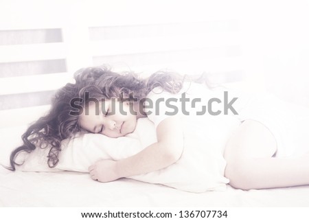beautiful little girl with curly hair  sleeping on a pillow in bed