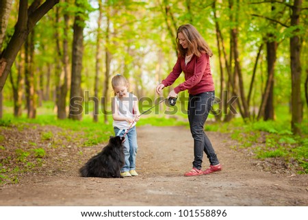 Mother and Daughter playing with  Dog in the forest