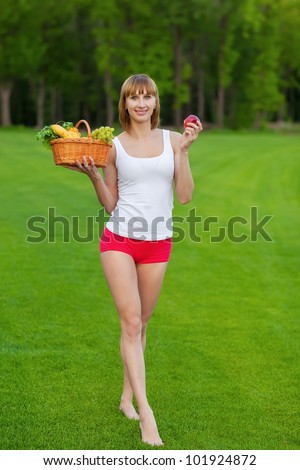 Young sportive woman with basket of fruits after fitness exercise