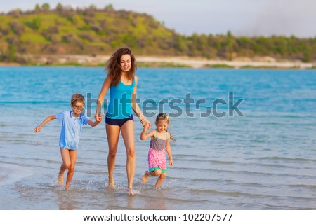 Happy mother with children running at the beach