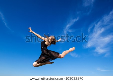 Freedom concept. Dancer jumping against blue sky wearing black