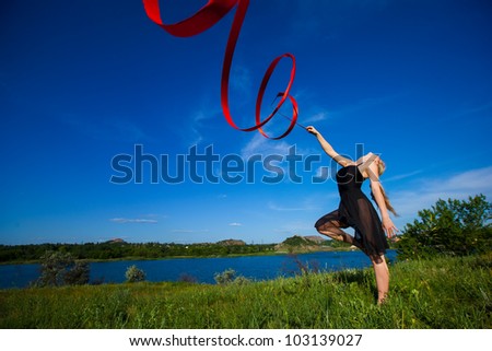 Young girl doing rhythmic gymnastics exercises with ribbon outdoor