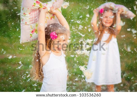 Happy childhood:little girls having fun with pillows outdoor