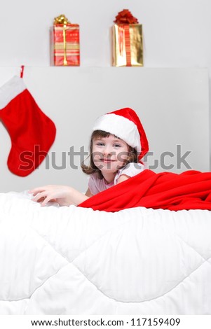 adorable kid girl sitting on her bed and holding a Christmas gift