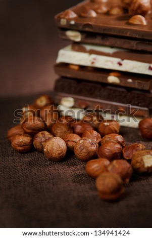 Close-up of stacked assorted chocolate with nuts on brown canvas