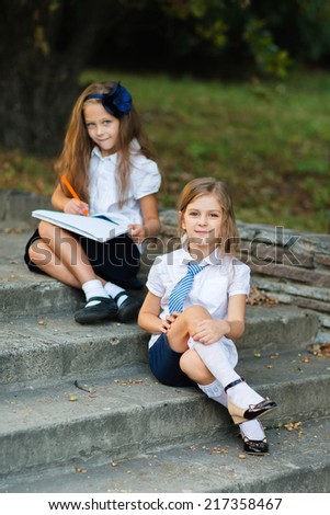 Two girls in school uniform  studying at the park