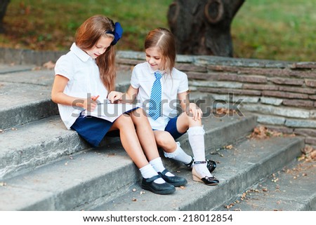 Two girls in school uniform studying at the park