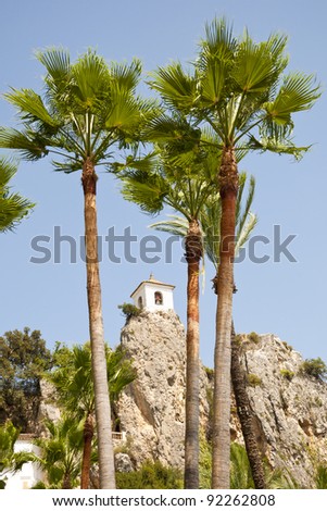 Belfry behind Palm Trees. This tower belongs to Alcozaiba fortress, built by muslims at XI century. Picture taken in El Castell de Guadalest, Alicante, Spain.