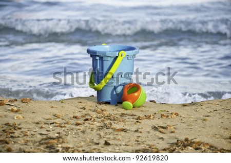 Toys on the beach. Plastic bucket for building sand castle and watering can