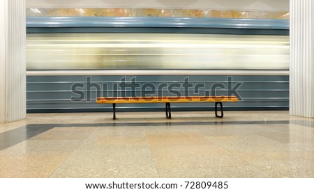 Bench on the platform with moving fast train
