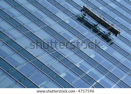 Window washers on scaffold against the side of a glass skyscraper - horizontal composition.