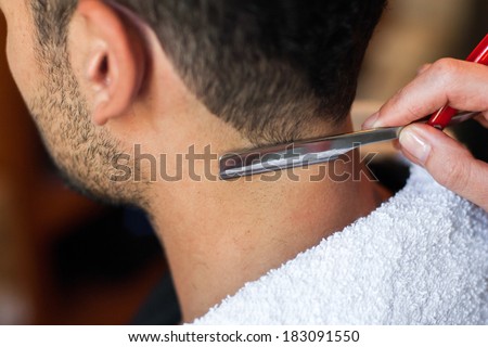 Hairdresser shaving man\'s neck with a straight razor