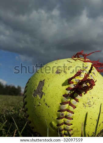 Worn, frayed softball in grass