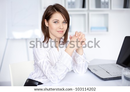 Portrait of beautiful young business woman sitting at desk at office