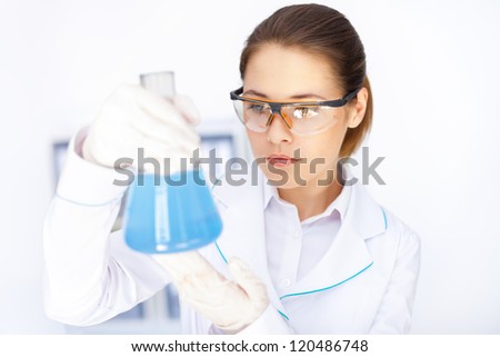 Young chemical female researcher holding flask in laboratory