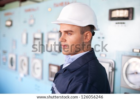Portrait of young engineer with helmet at control room
