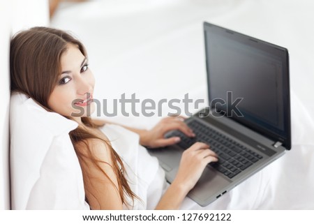 Portrait of beautiful young woman with laptop on bed