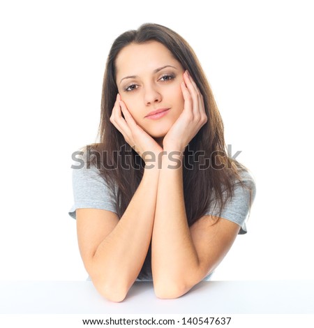 Portrait of pretty young brunette woman with elbows on the table and chin based on the hands isolated on white background