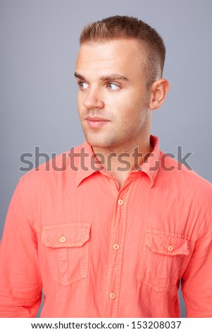 Portrait of  happy smiling young man wearing a red shirt on gray background