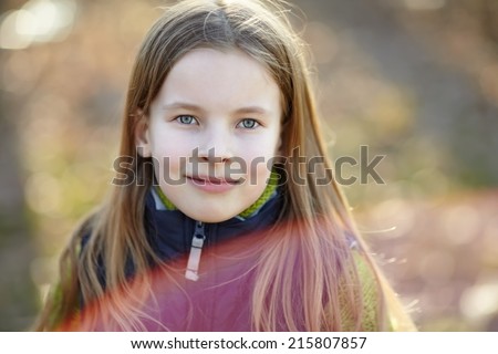Close-up portrait of cute little girl in the autumn park. Portrait of red flare from sun