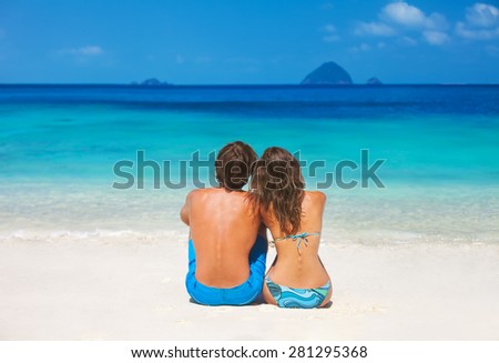 Back view of a couple sitting on the tropical beach during summer vacation