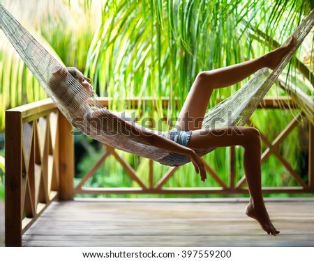 Young beautiful woman relaxing in hammock in a tropical resort