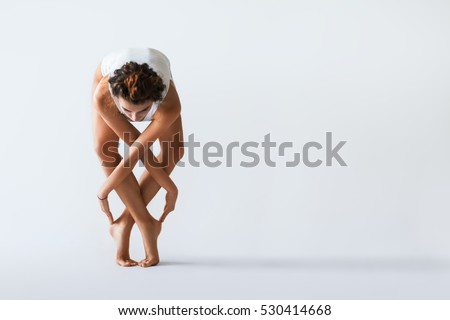 Young beautiful dancer posing on a studio background with copy space