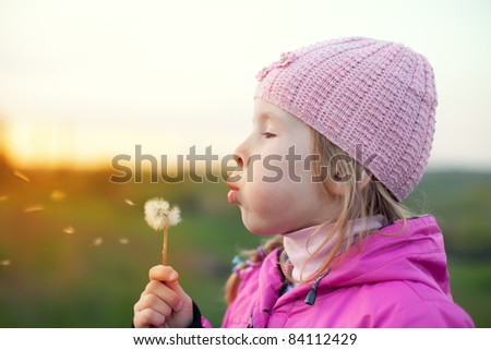 little girl in cap with dandelion at sunset in autumn