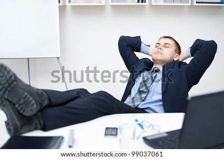 Tired businessman sleeping on chair in office with his legs on the table