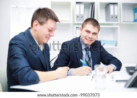 Two happy young business men working together in the office