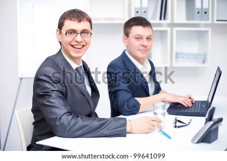 Two happy young business men working together at office
