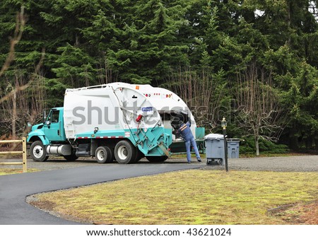A Sanitation Worker dumps a trash can into a garbage truck.