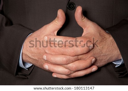 Man in suit clasped fingers in front of him closeup