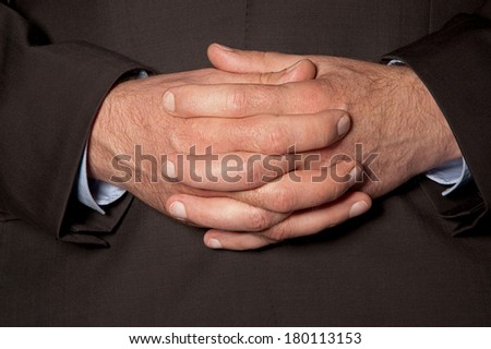 Man in suit clasped fingers in front of him closeup