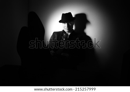 Man in suit and black hat at the age of forty-six years old looking at the camera  on the background of a rough wall with texture