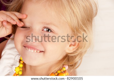 Cheerful little girl closing one eye close-up