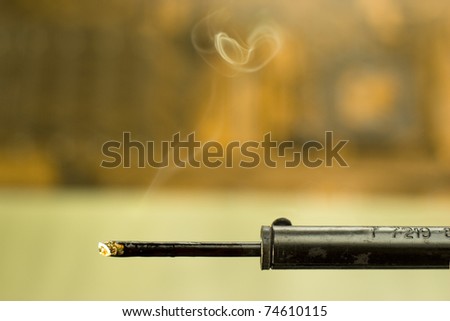 closeup of heated soldering iron with smoke on blurred background
