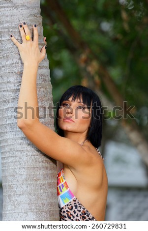 Woman posing with arms on the side of a tree