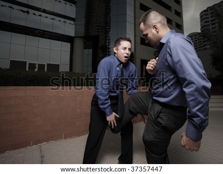 Businessman kicking the other businessman in the groin