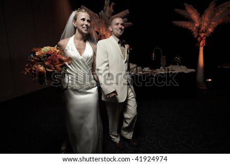 Bride and groom walking into the reception party after being married.  Image part of wedding series 1