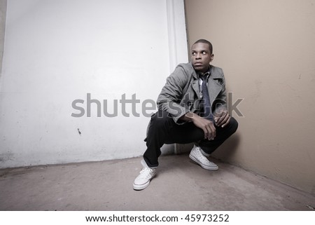Man crouching in a corner of a building