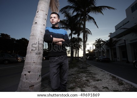 Man leaning on a tree with arms crossed